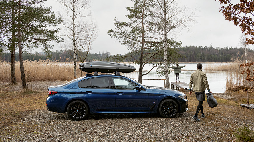 BMW med takbox parkerad framför en sjö.